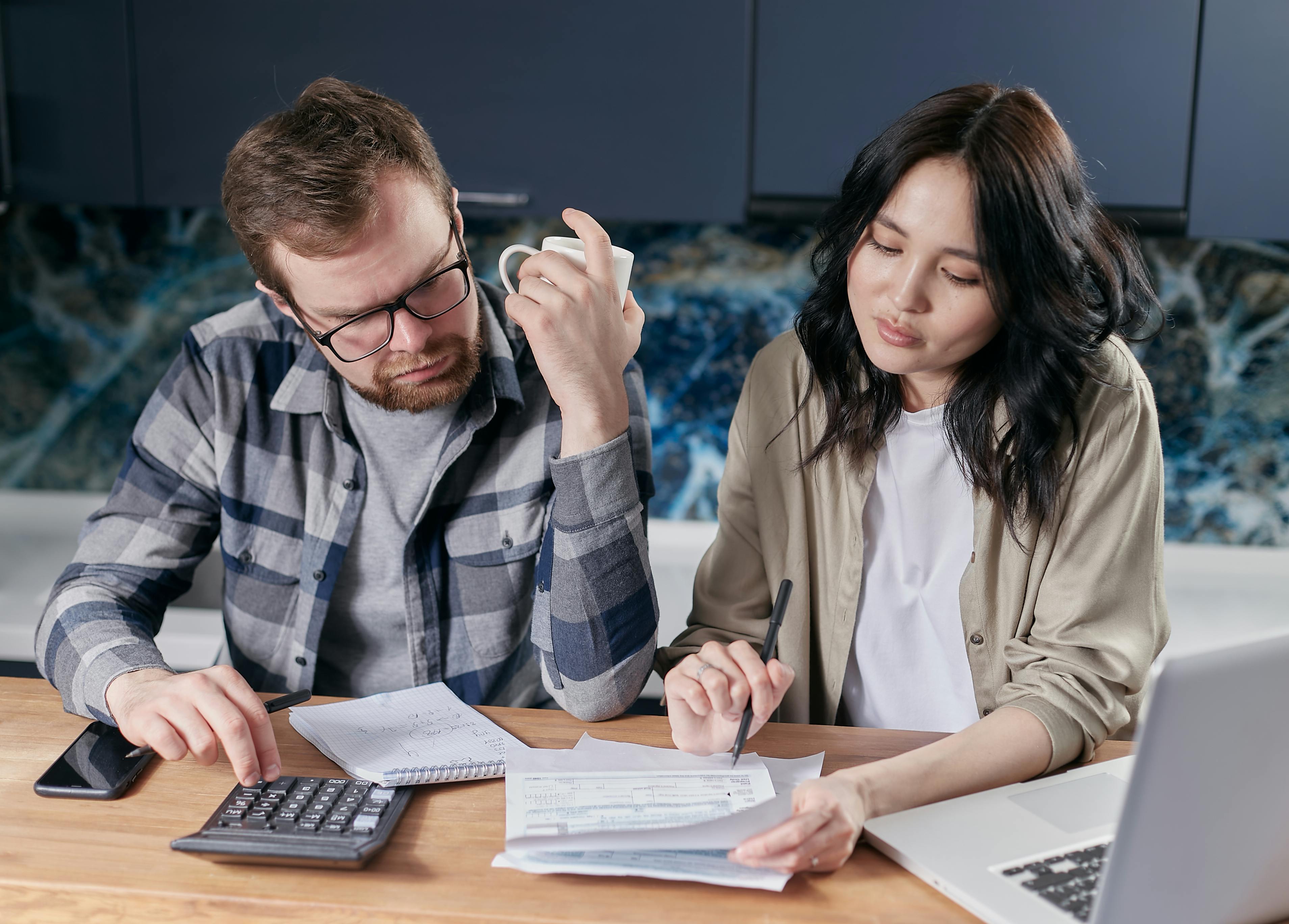 Couple reviewing bills and financial paperwork at a kitchen table