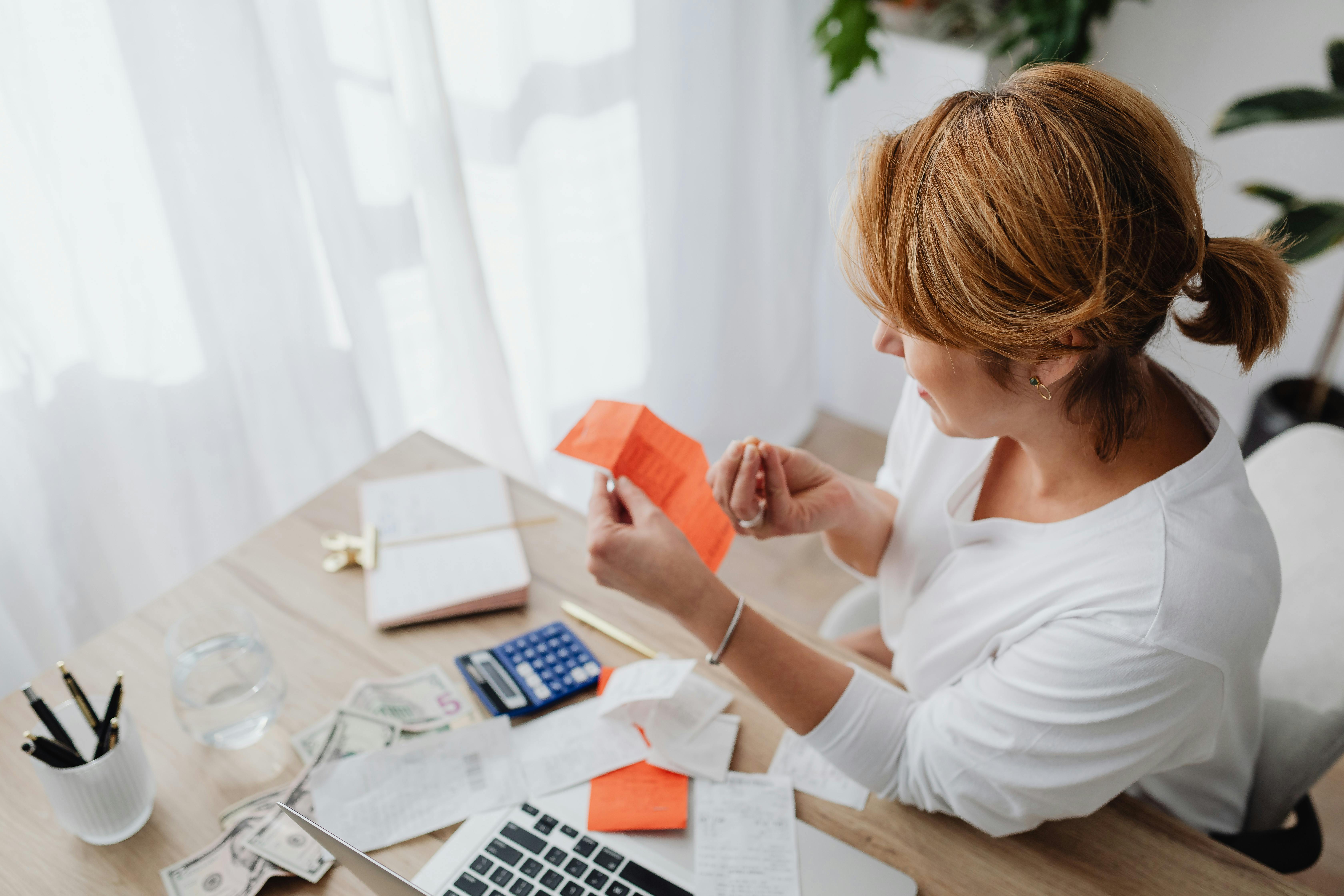 Woman reviewing receipts and budgeting paperwork at a desk with a calculator
