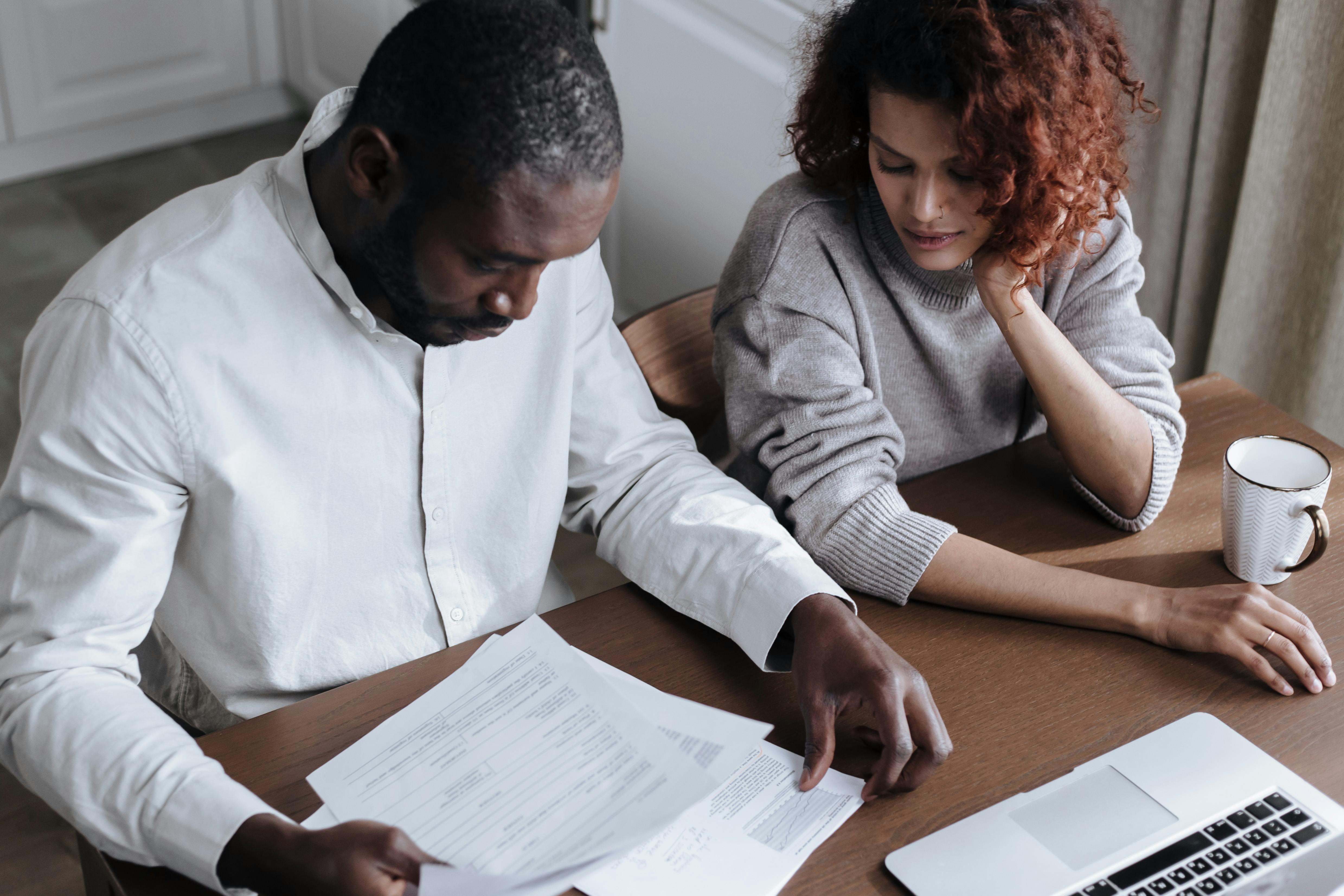 Couple reviewing bills together at a table with a laptop and calculator